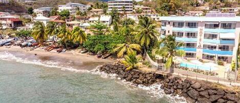 A coastal town with a beach, palm trees, and buildings.