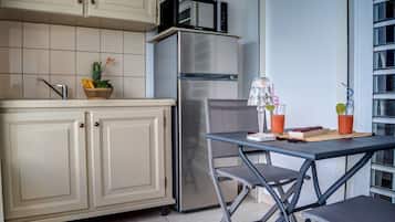 Una cocina compacta equipada con refrigerador, microondas y un pequeño comedor con mesa y sillas.