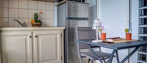 A compact kitchen with a refrigerator, microwave, and a small dining area with a table and chairs.