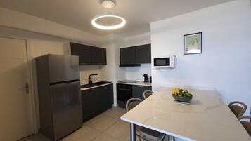 A modern kitchen with a refrigerator, stove, microwave, and dining table with chairs.