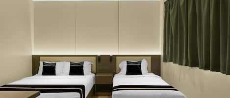 A hotel room with two beds, a small table, and a wardrobe.