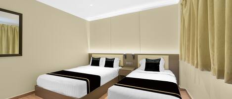 A hotel room with two beds, a wooden floor, beige walls, and a large window with curtains.