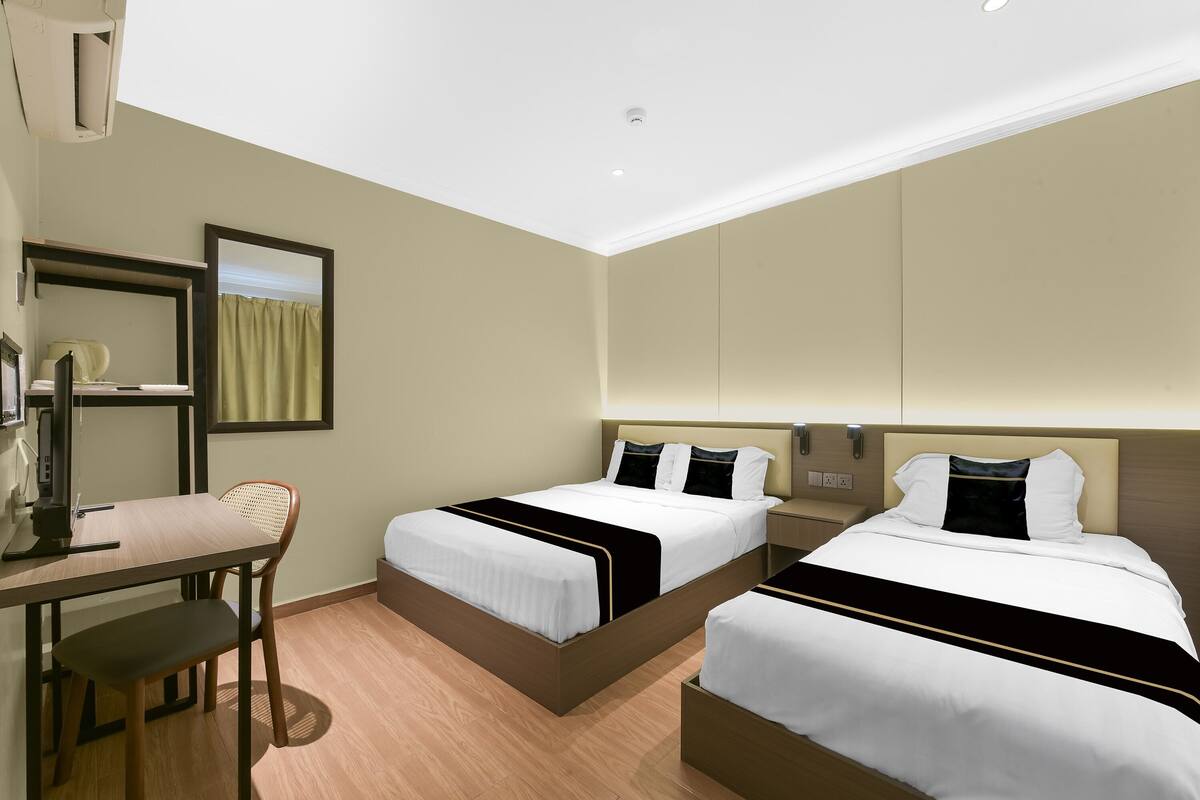 Habitación de hotel con dos camas, un escritorio y una silla.