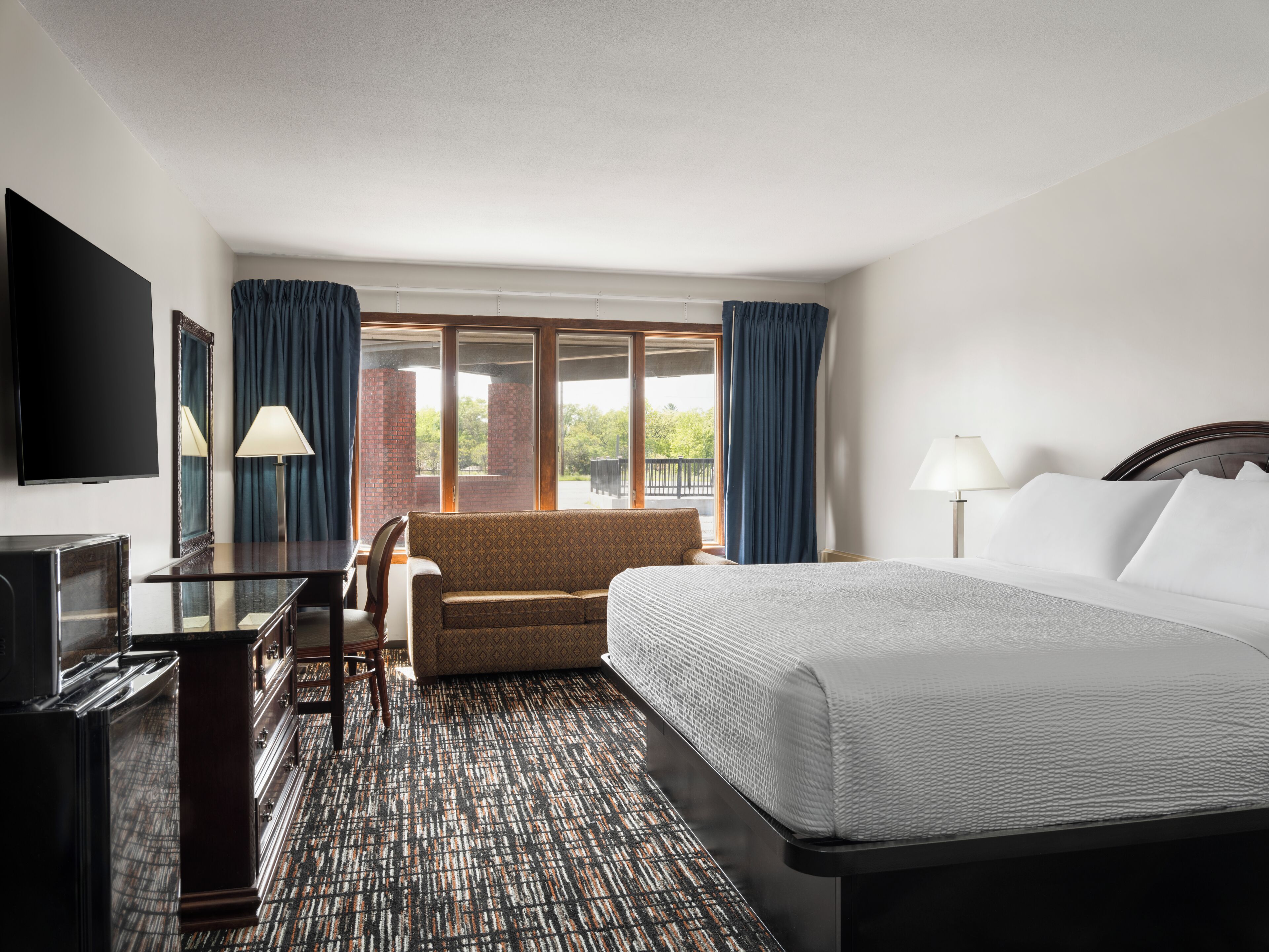 A hotel room with a bed, a sofa, a TV, and a desk.