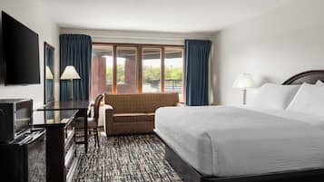Una habitación de hotel con cama, sofá, televisor y escritorio.