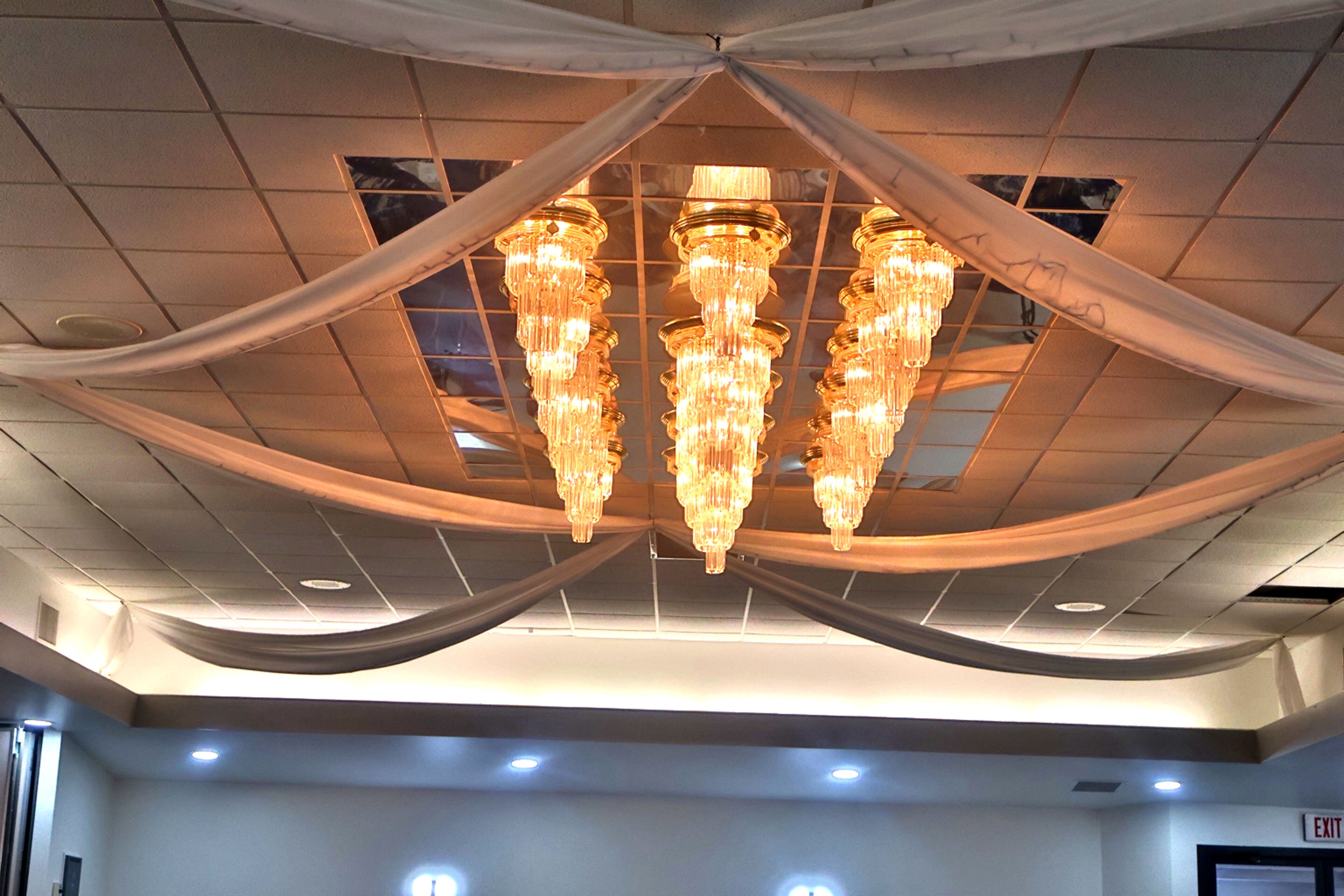 A ceiling with chandeliers and draped fabric.