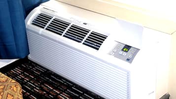 Un appareil de climatisation blanc, doté d’un panneau de commande, est posé sur un tapis à motifs.