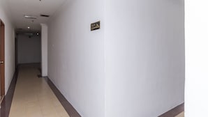 A hallway with white walls, a tiled floor, and a sign indicating the direction to the elevator. - Super OYO 1114 Neo Pegasus Hotel (Segamat)