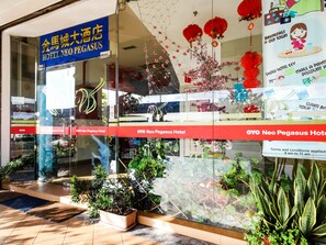 The exterior of the OYO Neo Pegasus Hotel with a large sign, glass entrance, and potted plants in front. - Super OYO 1114 Neo Pegasus Hotel (Segamat)