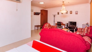 A spacious living room with a red sofa, a wooden cabinet, a TV, and a chandelier. - Super OYO 1114 Neo Pegasus Hotel (Segamat)