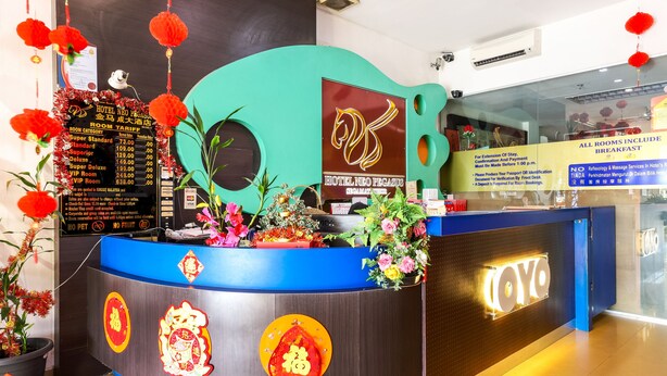 A hotel reception desk with a blue and brown color scheme, a digital display board, and traditional red decorations. - Super OYO 1114 Neo Pegasus Hotel (Segamat)