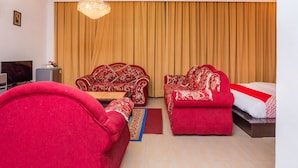 A hotel room with a large bed, two red sofas, a television, and a minibar. - Super OYO 1114 Neo Pegasus Hotel (Segamat)