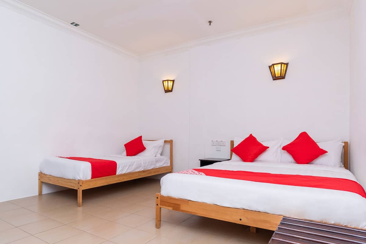 A hotel room with two wooden beds, white walls, and red accents.