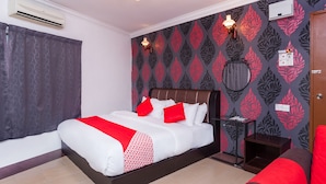 A hotel room with a bed, a nightstand, a mirror, and a door. - Super OYO 1114 Neo Pegasus Hotel (Segamat)