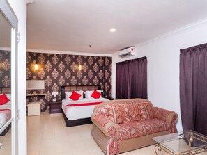 A hotel room with a bed, a sofa, a glass coffee table, a desk with a chair, and a wall-mounted air conditioner. - Super OYO 1114 Neo Pegasus Hotel (Segamat)