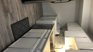 A compact hotel room with a kitchenette, a bed with a headboard, and a small bathroom area.