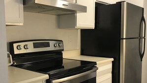 A modern kitchen with white cabinets, a stainless steel stove, and a black refrigerator.