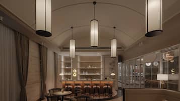 A modern bar area with high ceilings, pendant lighting, and a bar counter with stools.