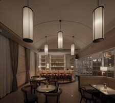 Una zona de bar moderna con techos altos, iluminación colgante y una barra con taburetes.