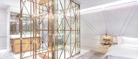 A modern bedroom with a geometric glass partition, a bed, a bedside table, and a nightstand.
