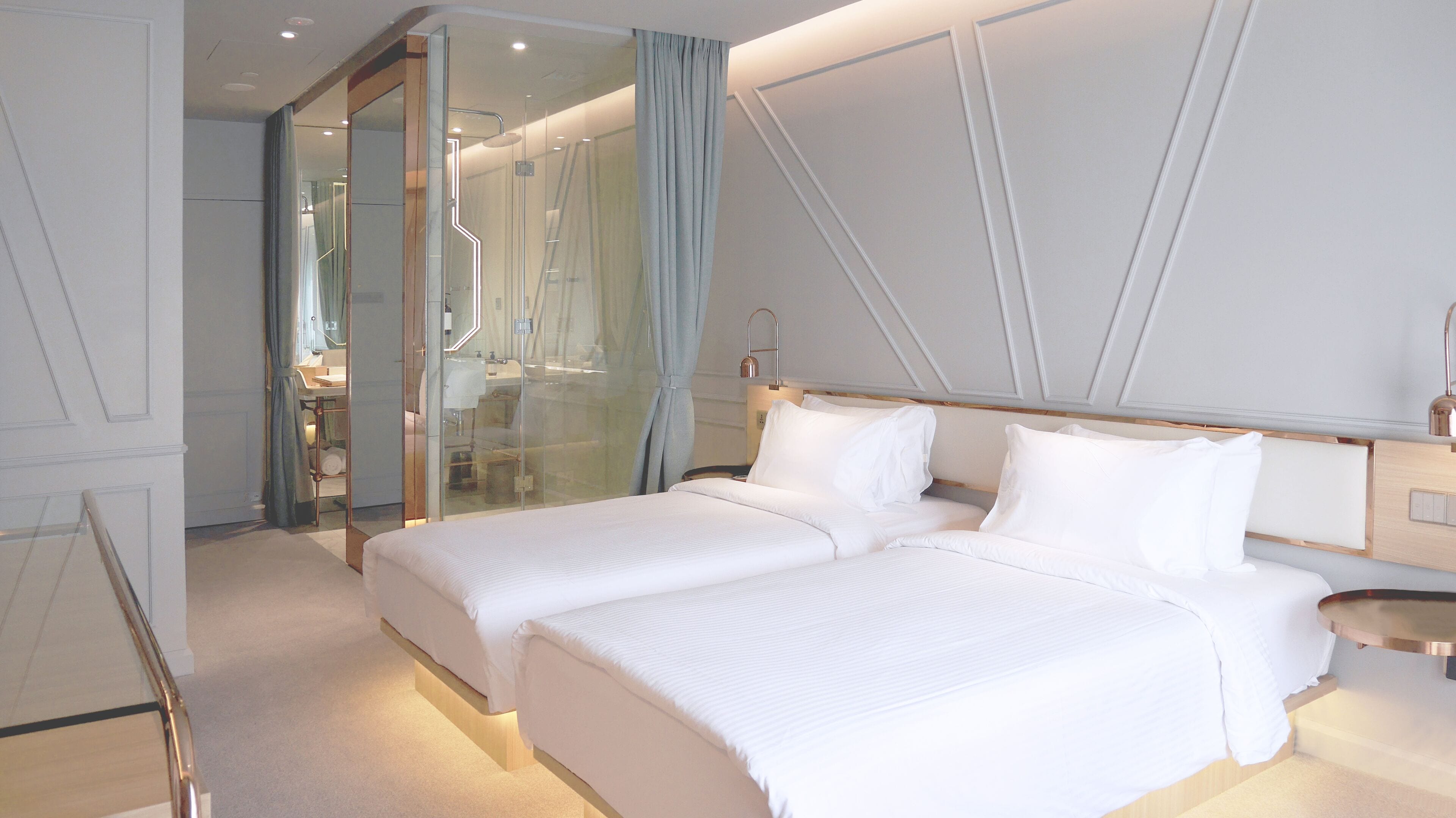 Ein modernes Hotelzimmer mit einem großen Bett, einer Duschkabine aus Glas und einem minimalistischen Design.