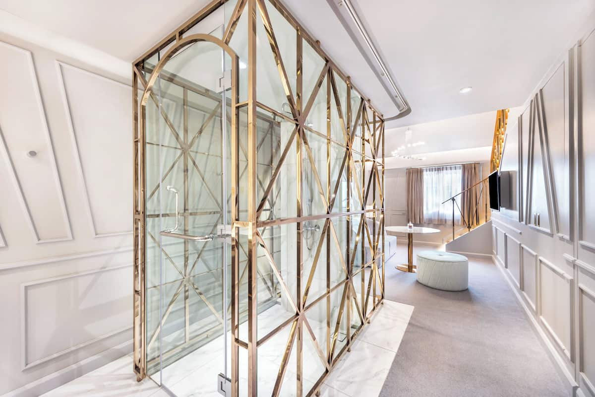 A modern hotel lobby with a glass partition, a round table, and a staircase.