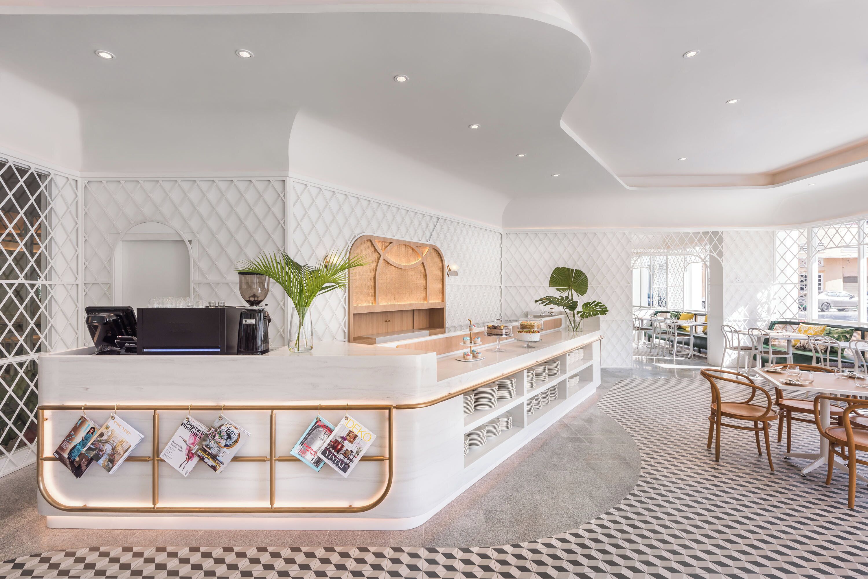 A modern reception area with a white counter, magazines, and a coffee machine.