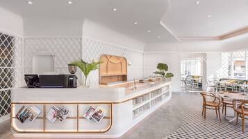 A modern reception area with a white counter, magazines, and a coffee machine.