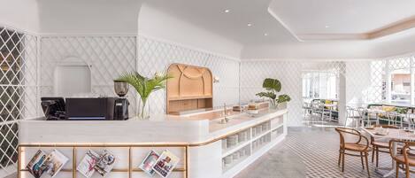 A modern reception area with a white counter, magazines, and a coffee machine.