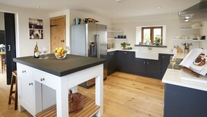 A modern kitchen with a central island, wooden flooring, and dark cabinetry.