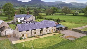 A stone farmhouse with a large yard and a covered porch.