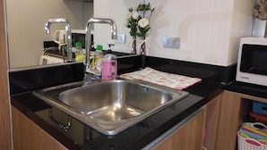 A compact kitchen with a stainless steel sink, a microwave, and a small cabinet. - Resort Style Condo @Heart of Bangkok- Quiet location- Fast Wifi -24 Hour Checkin (Bangkok)