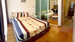 A modern bedroom with a large bed, a glass partition, and a small seating area with a sofa and a chair. - Resort Style Condo @Heart of Bangkok- Quiet location- Fast Wifi -24 Hour Checkin (Bangkok)