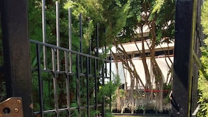 A gated entrance with a metal fence, a concrete pathway, and a view of a building with trees in the background. - Resort Style Condo @Heart of Bangkok- Quiet location- Fast Wifi -24 Hour Checkin (Bangkok)