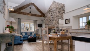 Un salon spacieux avec un mur en pierre, une table à manger en bois et un canapé bleu.