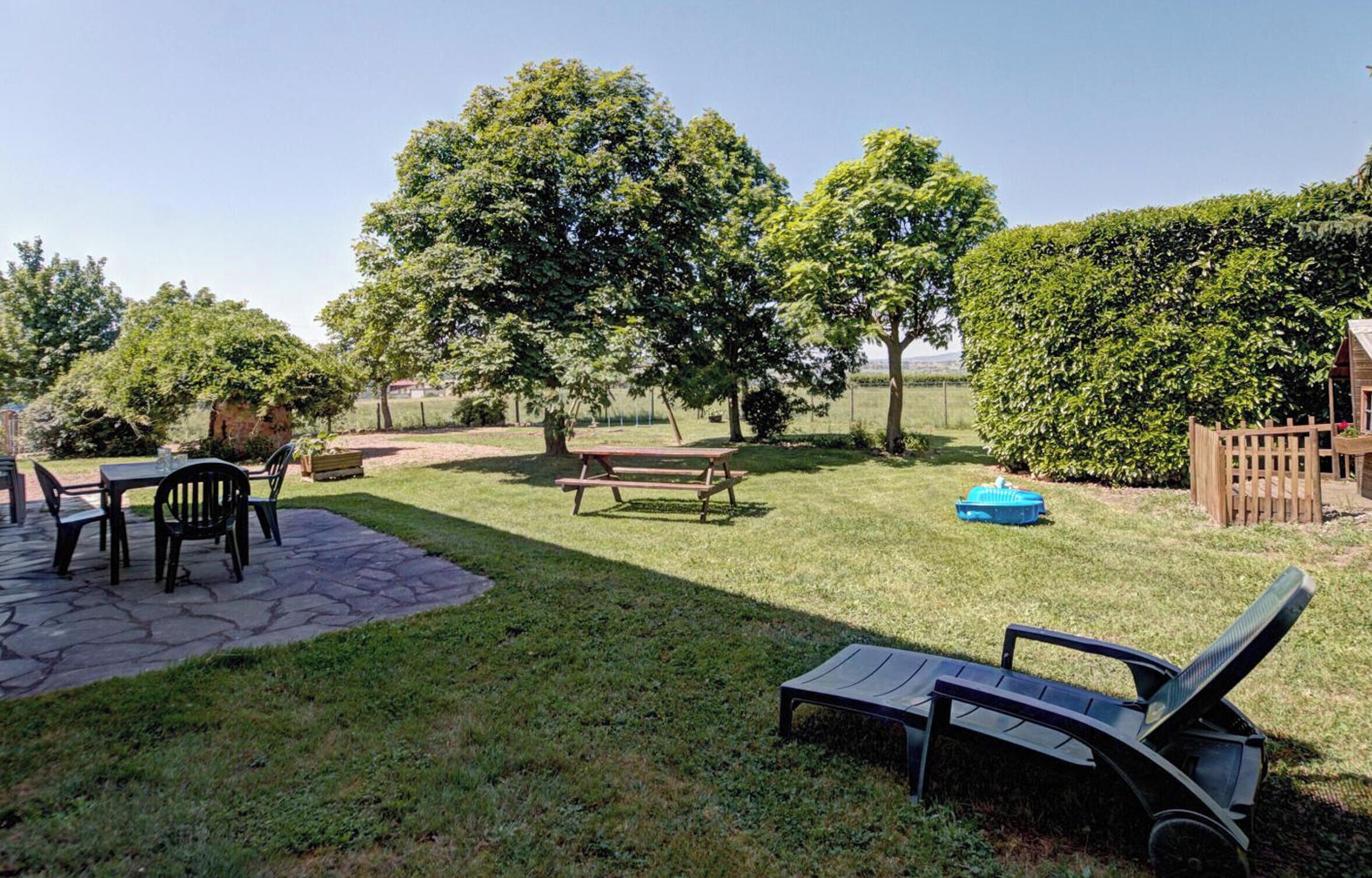 A patio area with a stone table and chairs, a wooden bench, and a lawn chair.