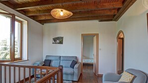 A cozy room with a wooden ceiling, a sofa, a chair, a small table, and a picture on the wall. - Cottage 80m² with Terrace, Wifi and Pets Allowed (Notre-Dame-de-Boisset)