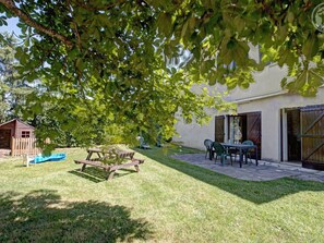 Un patio trasero con una mesa de picnic, sillas, una piscina pequeña y una cabaña de madera.