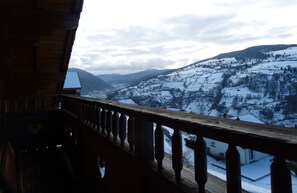 Un balcon offrant une vue sur des collines enneigées et une vallée.
