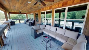 Une terrasse extérieure couverte, aménagée avec un canapé, des fauteuils et une table.