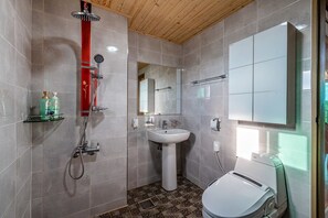 A modern bathroom with a shower, sink, toilet, and a large mirror.