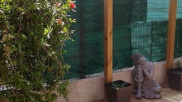 Eine Hollaube mit Kletterpflanzen und einer Buddha-Statue.