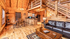 L’intérieur d’un chalet en bois comprend un coin repas, une cuisine et un canapé en cuir.