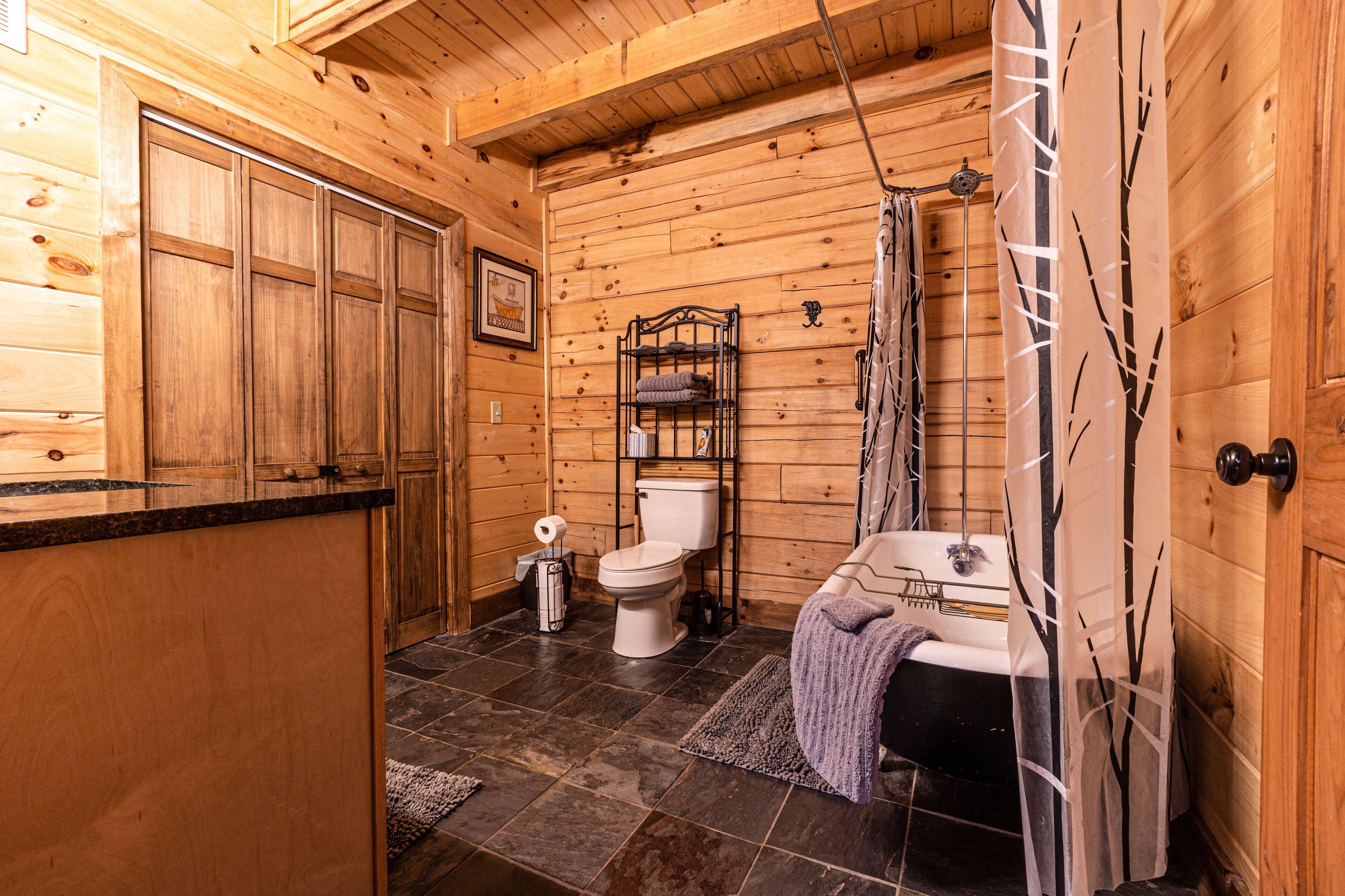 Baño de cabaña de madera con inodoro, lavabo y cortina de ducha.