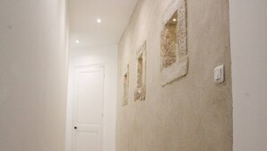 A narrow hallway with a white door at the end, beige walls, and a light switch on the right.
