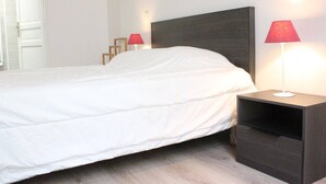 A neatly made bed with white bedding, a dark headboard, and two bedside tables with lamps.