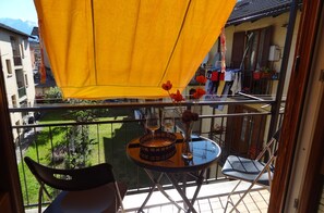 Enjoy a tranquil moment on this balcony with a garden view, featuring a table for two, a vase of flowers, and a comfortable seating area.