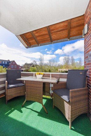Un patio cubierto con muebles de mimbre y una mesa, con vistas al vecindario.