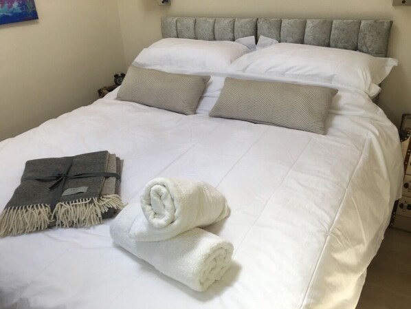 A neatly made bed with white linens, two pillows, and a folded towel. - Secluded, self-contained converted stable, Elstar. (Bristol)