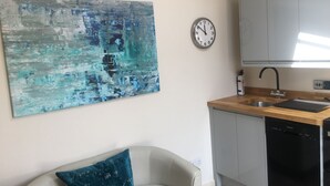 A modern kitchen with a wooden countertop, a dishwasher, and a wall-mounted clock.